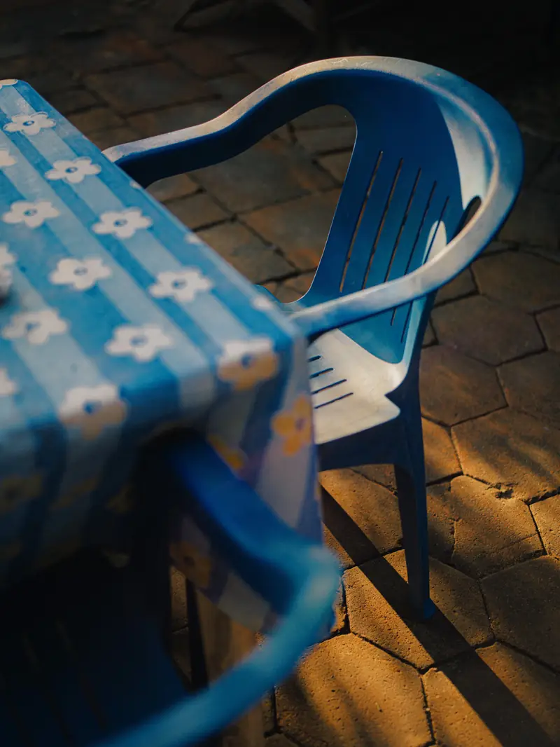 Blue plastic chair and checked tablecloth in late sun